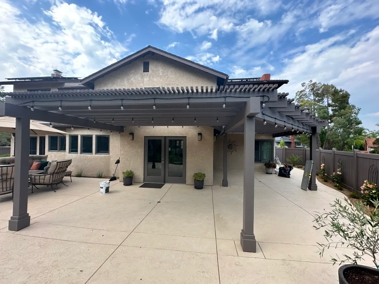 The whole rear elevation finished, furniture set out under the pergola.