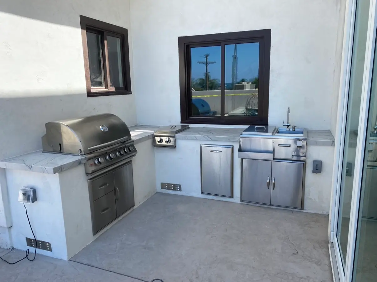 The finished kitchen in the corner by the slider, cooking end on the left, the counter turning the corner to the sink on the right.