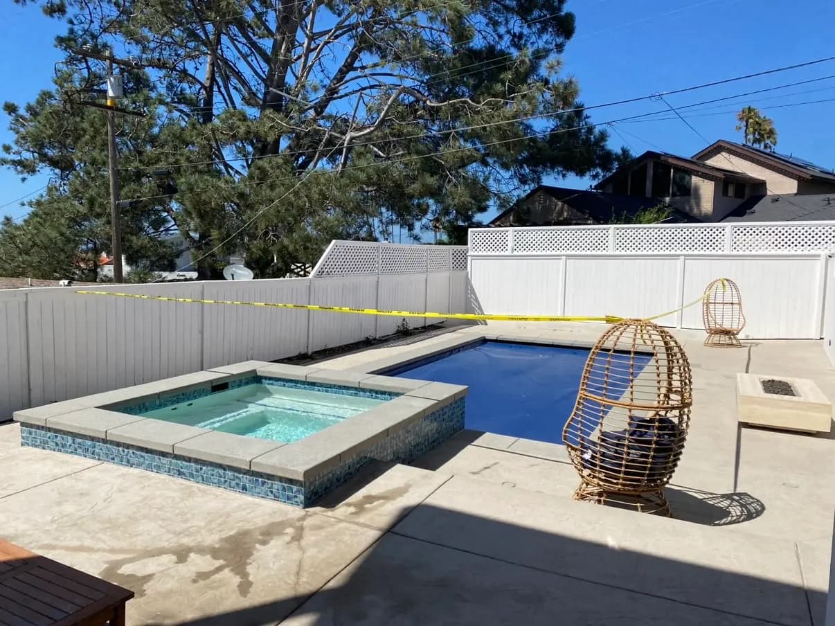 Yellow caution tape still runs across the yard, with the tiled spa in the foreground and a hanging wicker chair on the deck beside the covered pool.
