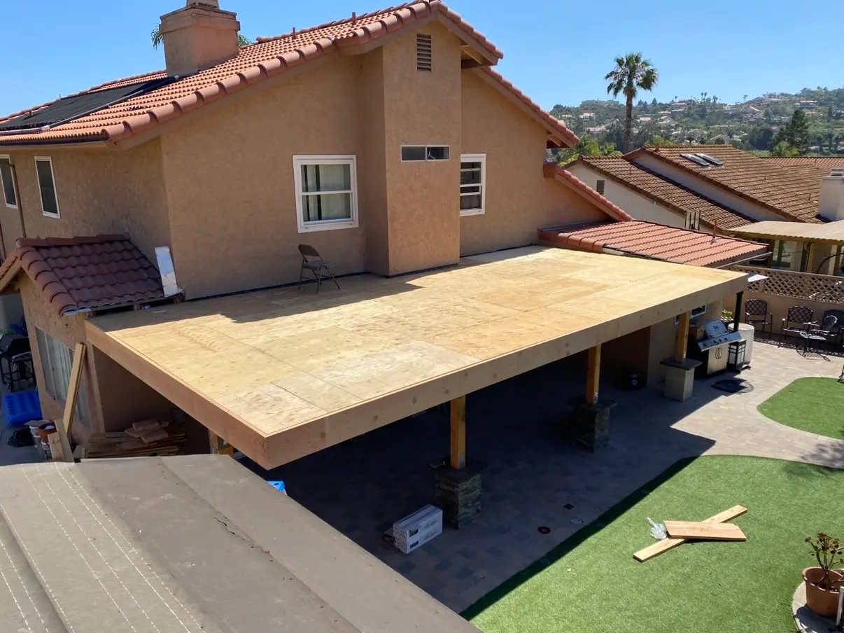 Deck framing and joists laid out over wrapped concrete footings before decking goes down