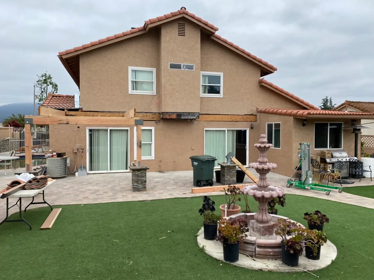 Two-story home with a new covered patio structure framed across the back