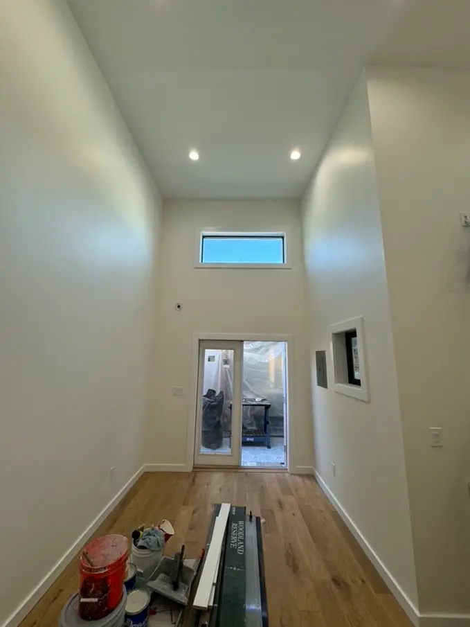 Finished high-ceilinged interior with recessed lighting and wood floors
